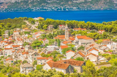 A charming view of Povlja, a picturesque coastal village on Brac Island, Croatia, featuring traditional stone houses, and the crystal-clear Adriatic Sea, capturing the essence of Dalmatian charm clipart