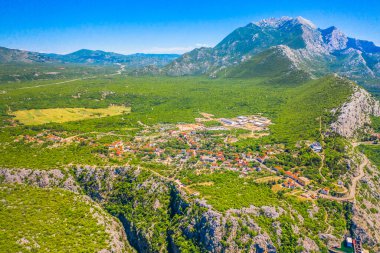Karst tepeleri, yeşil araziler ve Hırvatistan 'ın iç kesimlerine özgü geleneksel taş evlerle çevrili Dalmaçyalı Zagora' nın engebeli arazisine yuva yapmış Zadvarje adlı antika köyün havadan görünüşü