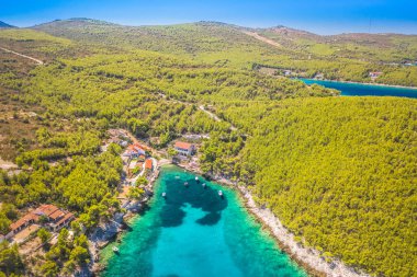 Hırvatistan 'ın Hvar Adası' ndaki tenha Pokrivenik Körfezi 'nin hava manzarasında kristal berrak turkuaz sular, dramatik kayalık kıyı şeridi ve huzurlu bir ortamda yemyeşil Akdeniz bitkileri yer alıyor.