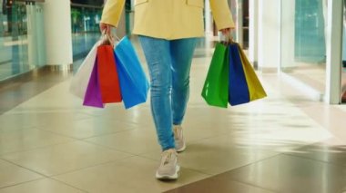 Alışveriş merkezine giden kadını yakından görmek, elinde dükkandan bir sürü renkli kağıt paketler tutuyordu. Alışverişten sonra kadın