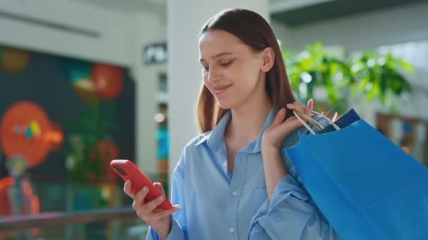 使用智能手机的女顾客用纸袋装着她的购物袋微笑 女人拿着购物袋 用手机 年轻女子购物后与朋友闲聊 — 图库视频影像