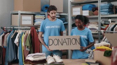 Bağış sözcüğüyle kameraya bakıp gülümseyen çok ırklı meslektaşların portresi. Organizasyonda çalışan gönüllüler ve bağışlanan kıyafetleri sıralamak