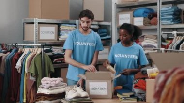 Çeşitli erkek ve kadın gönüllüler kitapları ayırıp bağış merkezindeki dolaba koyuyorlar. İnsani yardım ve bağış konsepti