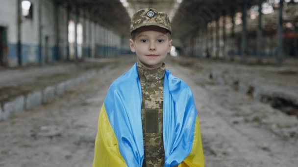 Hazafias Katona Áll Ukrán Zászlóba Csomagolva Romok Hátterében Kamerát Nézi — Stock videók
