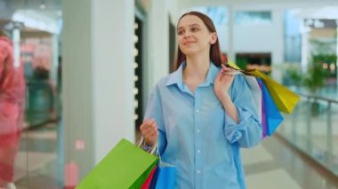 Şık giyinmiş genç bayan müşteri alışveriş yaptıktan sonra kendini mutlu hissediyor. Alışveriş merkezine ya da ticaret merkezine bir sürü renkli paketle giden bir alıcı. Elinde bir sürü paket olan gülümseyen kadın.