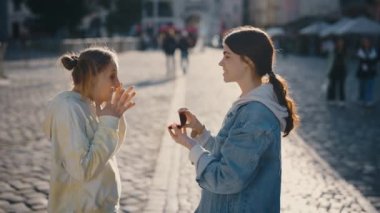 Genç homoseksüel kadın eşcinsel şehir merkezindeki sevgilisine sürpriz bir evlilik teklifi yapıyor. Kadın duygusal olarak kabul ediyor ve sevgiyle sarılıyor.