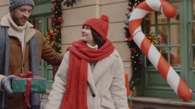 Kendini mutlu hisseden adam sevgilisine Noel hediyesi veriyor ve sonra da birlikte sarılıyor. Şaşırmış kadın mutlu çünkü kocası ona büyük bir Noel hediyesi veriyor.