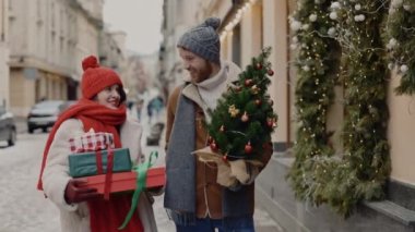 Çift yürüyor, güzel konuşuyor ve Noel hediyeleri ve ağaç taşıyor. Kafkas ailesi noel pazarından eve dönüyorlar. İnsanlar ve tatil kavramı