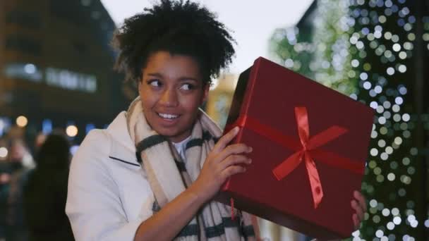 African American Woman Shaking Gift Box Trying Guess What Standing — Stock Video