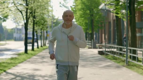 成熟微笑的跑步者正在街上跑步 一边听着音乐一边训练 体育与健康生活方式概念 — 图库视频影像
