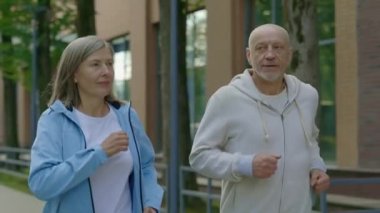 Yetişkin çiftin sokakta koşup birbirleriyle konuşmalarını yakından görmek. Spor ve sağlıklı yaşam tarzı kavramı. Gençlik Yaşlanma