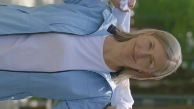 Yetişkin bir kadının kameraya baktığı dikey video eğitimden sonra boynunda bir havlu taşıyor. Spor ve sağlıklı yaşam tarzı kavramı. Gençlik Yaşlanma