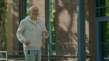 Sokakta koşan ve eğitim için müzik dinleyen olgun bir koşucunun yan görüntüsü. Spor ve sağlıklı yaşam tarzı kavramı. Gençlik Yaşlanma