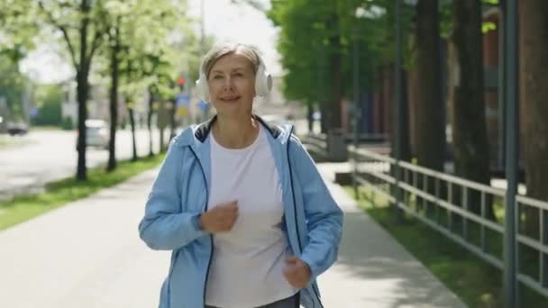Olgun Bir Kadın Koşucu Sokakta Koşuyor Kulaklık Takıp Müzik Dinlerken — Stok video