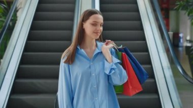 Portre, alışveriş sonrası mutlu hisseden kadın müşteriye gülümsedi. Alışveriş merkezinde elinde bir sürü renkli paketle bekleyen bir alıcı. Mutlu Kafkas kadın tutuşu ve bir sürü paket