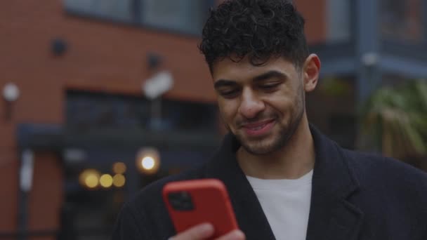 Χαμογελαστή Πολυεθνική Άνθρωπος Στέκεται Έξω Και Χρησιμοποιώντας Smartphone Γραπτών Μηνυμάτων — Αρχείο Βίντεο