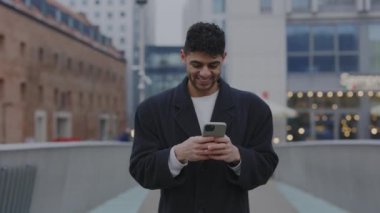 Şehre inen müşterilerle mesajlaşan çok ırklı bir adam gülümsedi. Erkek, arkadaşlarıyla cep telefonu kullanarak iletişim kurmaktan mutlu. İnsanlar ve teknoloji kavramı