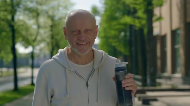 Зрілий Чоловік Тримає Пляшку Води Посміхається Камеру Портрет Старшого Бігуна — стокове відео