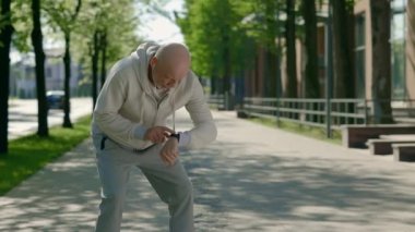 Yetişkin bir koşucu derin bir nefes almak için durur ve sabah koşusu sırasında kulaklık takarak akıllı saati kullanır. Spor ve sağlıklı yaşam tarzı kavramı