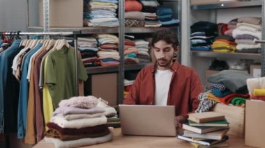Perakende veya butik mağazasında dizüstü bilgisayarla çalışan engelli bir erkek yönetici kontrol listesindeki giyim stoklarını kontrol ediyor. Bağımsız küçük işletme, mağaza konsepti, girişimci