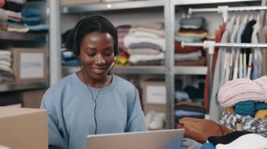 Bilgisayarın başında oturan ve perakende veya butik dükkanında çalışırken müşteriyle sohbet eden engelli bir bayan yönetici. Bağımsız küçük işletme, mağaza konsepti, girişimci