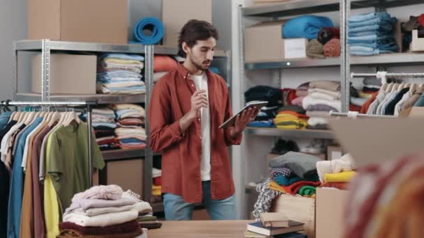 Travailleur Masculin Debout Entrepôt Tapant Tablette Tout Triant Les Vêtements — Video