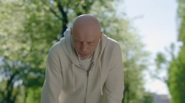 Son sınıf erkek koşucu derin bir nefes almak için koştuktan sonra duruyor ve sabah sokakta kulaklık takarak akıllı saat ekranını kontrol ediyor. Spor, teknoloji ve sağlıklı yaşam tarzı konsepti