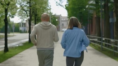 Fitness 'in arka görüntüsü, aktif ve sağlıklı yetişkin bir çift sokakta birlikte koşuyor. Ailesi sabah antrenmanında eğleniyor. Spor ve sağlıklı yaşam tarzı kavramı. Gençlik Yaşlanma