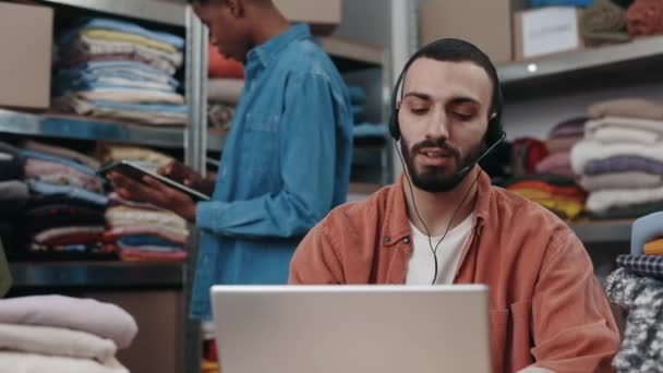 Szczęśliwy Niepełnosprawny Menadżer Rozmawiający Klientem Słuchawkami Pracujący Laptopie Sklepie Odzieżowym — Wideo stockowe