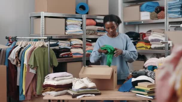 多人種の女性労働者が服を折り 再利用センターの倉庫の食器棚に入れます 人道支援と第二の手の概念 全長表示 — ストック動画