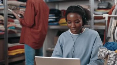 Çevrimiçi kıyafet mağazasında çalışan çok ırklı bir kadın, operatör kulaklığı takıyor. Ev ofisinde çalışan kadın yönetici. Küçük işletme ve çağrı merkezi kavramı