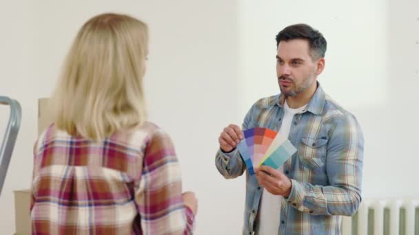 男性设计师帮助女性客户选择新房墙面的颜色 男工们手握短袜 讨论着公寓里墙壁的颜色 — 图库视频影像