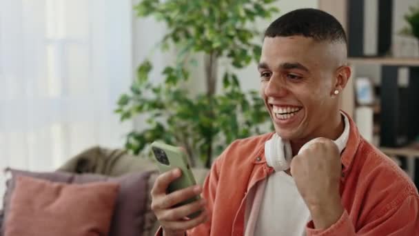 Sorpreso Afroamericano Una Vittoria Celebrativa Smartphone Seduto Sul Divano Appartamento — Video Stock