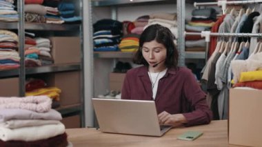 Beyaz kadın yönetici bir müşteriyle dizüstü bilgisayar kullanarak konuşuyor. Hem de online giyim mağazasında çalışırken. Destek servisi. Küçük işletme kavramı