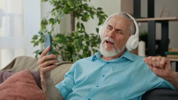 Ανώτερος Καυκάσιος Που Ακούει Μουσική Κρατώντας Τηλέφωνό Του Ενώ Κάθεται — Αρχείο Βίντεο