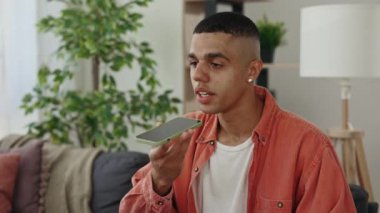 Gülümseyen Afrikalı Amerikalı genç adam işten sonra koltukta oturan bir sesli mesaj kaydediyor..