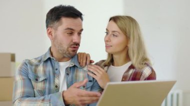 Beyaz bir aile yeni evlerinde dizüstü bilgisayar kullanarak tamir odasını tartışıyor. Mutlu çift yeni dairelerini bilgisayarda tasarlıyor. Yer değiştirme ve teknoloji kavramı