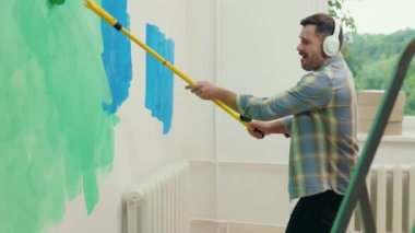 Neşeli işçi duvarları boyuyor ve evde müzik dinleyip kulaklık takıyor. Yurtiçi faaliyetler, teknoloji ve insan konsepti