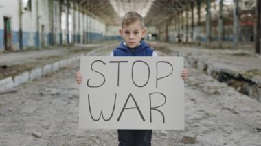 Ciddi sarışın çocuğun portresi savaşı protesto ediyor. Yazıtla pankartı tutuyor. Savaşı durdurun. Savaşı durdurma çağrısı, savaşa karşı çocuk, Ukrayna 'da kriz