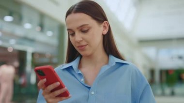 AVM 'de dikilip akıllı telefon kullanan çekici beyaz kadın. Telefondaki mesajdan sonra bayan müşteri. İnternetten alışveriş