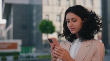 Heyecanlı, çok ırklı genç bir kadın akıllı telefonundaki iyi mesajla seviniyor. Cep telefonuna bakan mutlu iş kadını zaferi kutluyor. İyi haber ve teknoloji sektörü konsepti