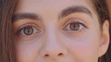 Close up of charming caucasian woman eyes with looking at camera. Outdoors portrait of pretty brunette face. Youth and beauty concept