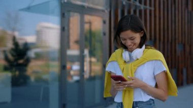 Business woman walking near the business centre, using smartphone for working purposes. Female manager. Texting message online. Asian it worker working near the office centre