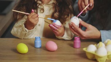 Happy easter. Coloring eggs close-up. Mom and daughter preparing for Easter, painting and decorating eggs. Christian celebration, family traditions