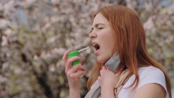 白人の不幸な女性は彼女の喉をスプレーで治療し 彼女の口の中にそれを振りかける 体調不良の女性は屋外で気分が悪くなる 人と病気の概念 — ストック動画