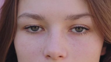 Close up eyes of pretty young woman with freckles on fresh healthy skin looking at camera with natural brown eyebrows. Youth and beauty concept