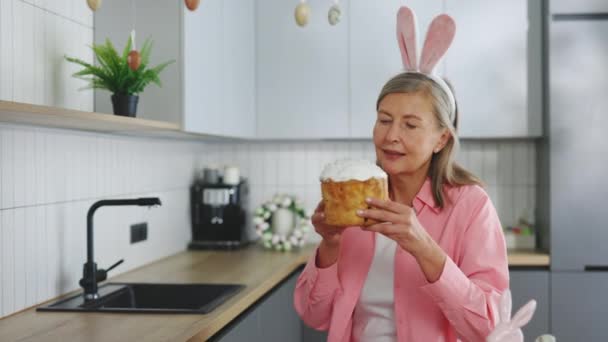 Літня Леді Носить Вуха Кролика Сидячи Кухонному Столі Їдячи Великодній — стокове відео