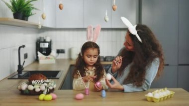 Bir anne ve kız mutfakta oturup geleneksel bahar yemeği için yumurta boyuyor. Mutlu bir aile Paskalya için hazırlanıyor. Paskalya, aile, tatil ve çocuk konsepti