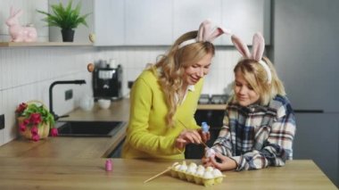 Mother and son in kitchen sitting, painting eggs for traditional spring easter dinner. A happy family is preparing for holiday. Easter, family, holiday and children concept