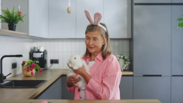 Портрет Пожилой Женщины Пушистым Пасхальным Кроликом Носящей Кроличьи Уши Улыбающаяся — стоковое видео